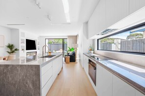 Una cocina moderna con una isla grande, electrodomésticos integrados y vistas al exterior.