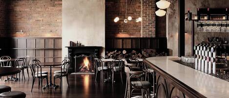 A bar area with a fireplace, seating, and a bar counter with taps.