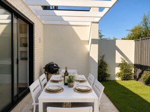 An outdoor patio with a dining table set for four, surrounded by white chairs. - The Avenue - Brand New Luxury, Walk to Main Street (Mornington)