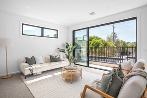 A modern living room with a sofa, coffee table, and a view of the outdoors through large windows.