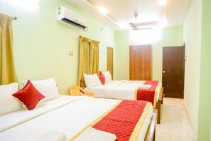 A hotel room with two beds, a ceiling fan, an air conditioning unit, and a wooden wardrobe. - Saraswathi Auro Residency (Vanur)