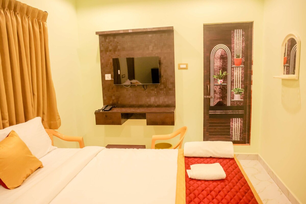 A hotel room with a bed, a desk with a telephone, a mirror, and a window with curtains.