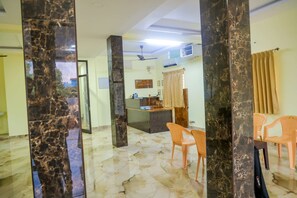 A room with a marble floor, a dining area with plastic chairs, a kitchen counter, and a ceiling fan. - Saraswathi Auro Residency (Vanur)