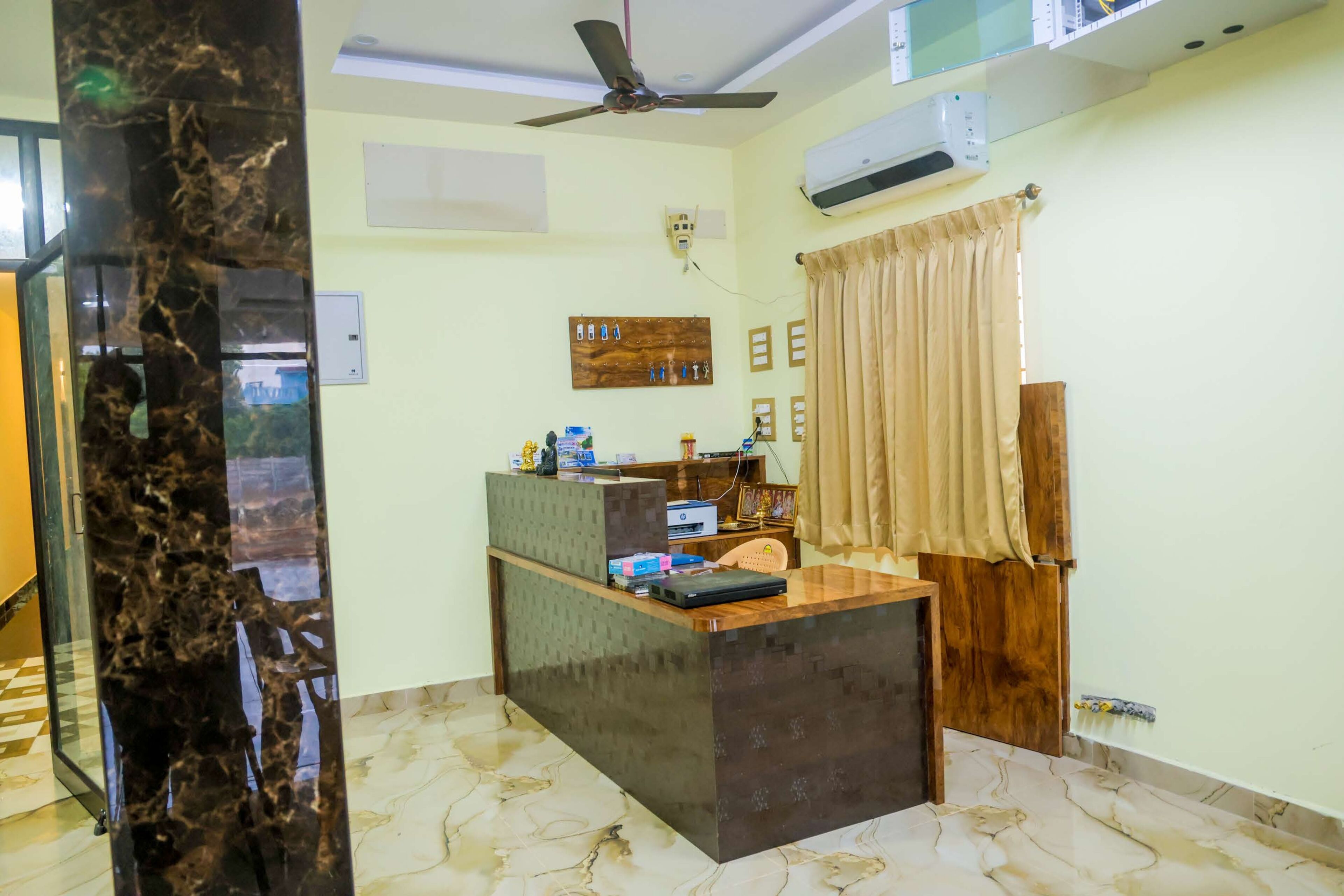 Una habitación con escritorio, ventilador de techo, aire acondicionado y ventana con cortinas.