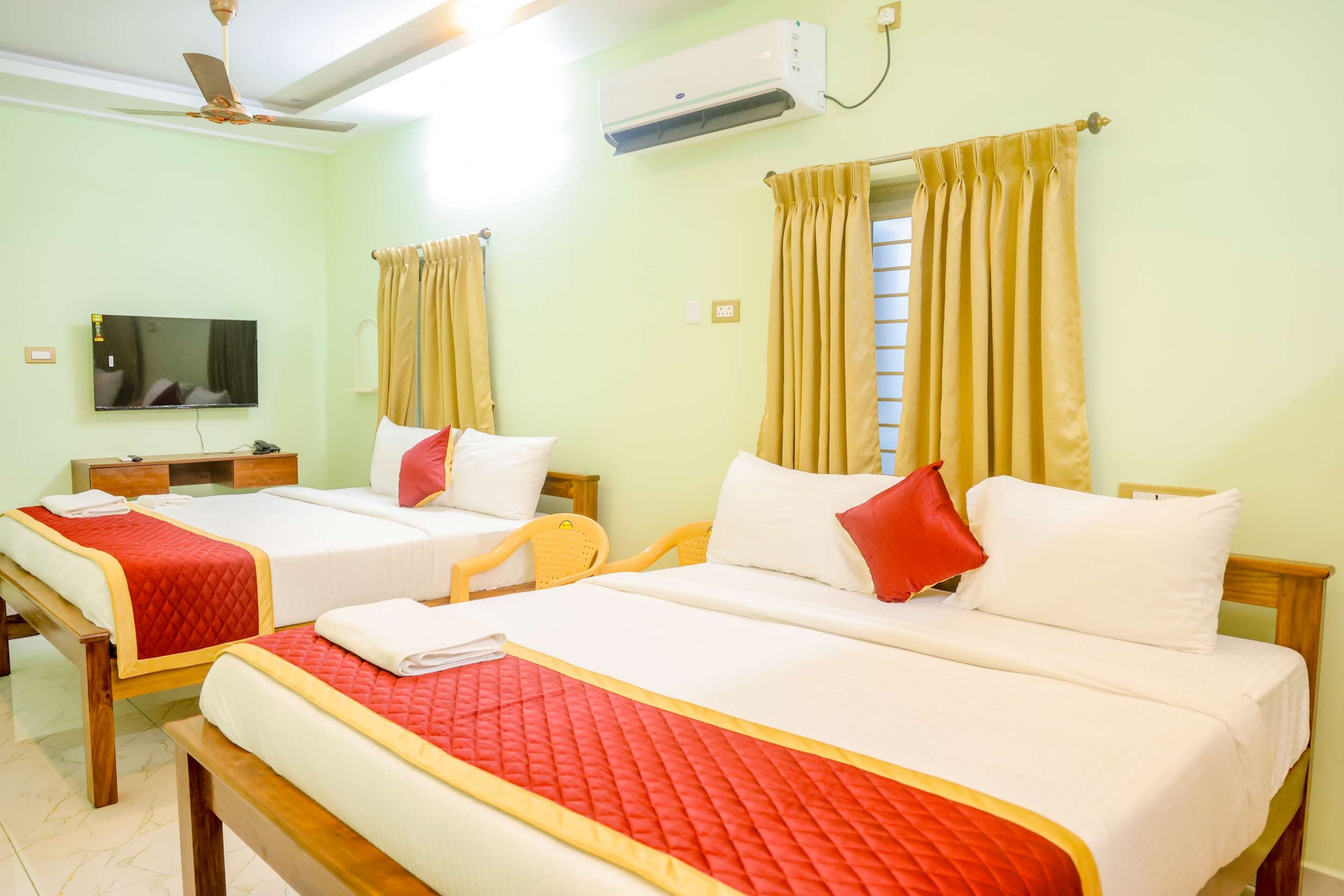 Habitación de hotel con dos camas, televisor, aire acondicionado y ventana con cortinas.