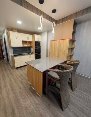 Eine moderne Küche mit Holzausstattung, einer zentralen Kochinsel und Korbstühlen.