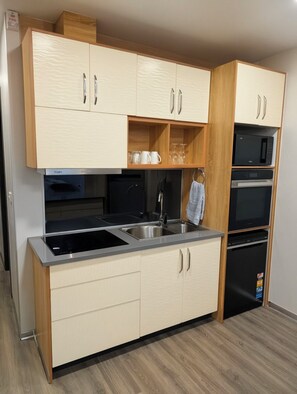 A modern kitchen with built-in appliances, including a microwave, oven, and dishwasher, and a stainless steel sink.