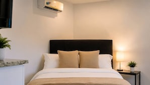 Ett hotellrum med en säng, ett nattduksbord, en lampa och en luftkonditioneringsanläggning.