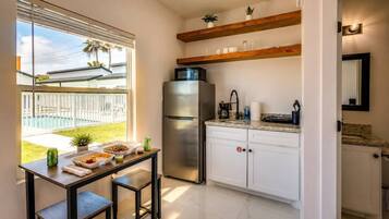 A modern kitchen with a stainless steel refrigerator, white cabinets, and a dining area with a table and chairs.
