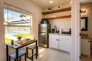 A modern kitchen with a stainless steel refrigerator, white cabinets, and a dining area with a table and chairs.