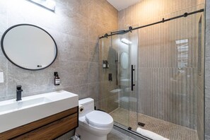 A modern bathroom with a glass-enclosed shower, a white sink, and a toilet. - Spruce Villa - 2nd Floor Queen Studio (Philadelphia)