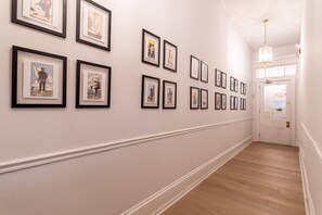A hallway with framed artwork on the walls and a wooden floor. - Spruce Villa - 2nd Floor Queen Studio (Philadelphia)