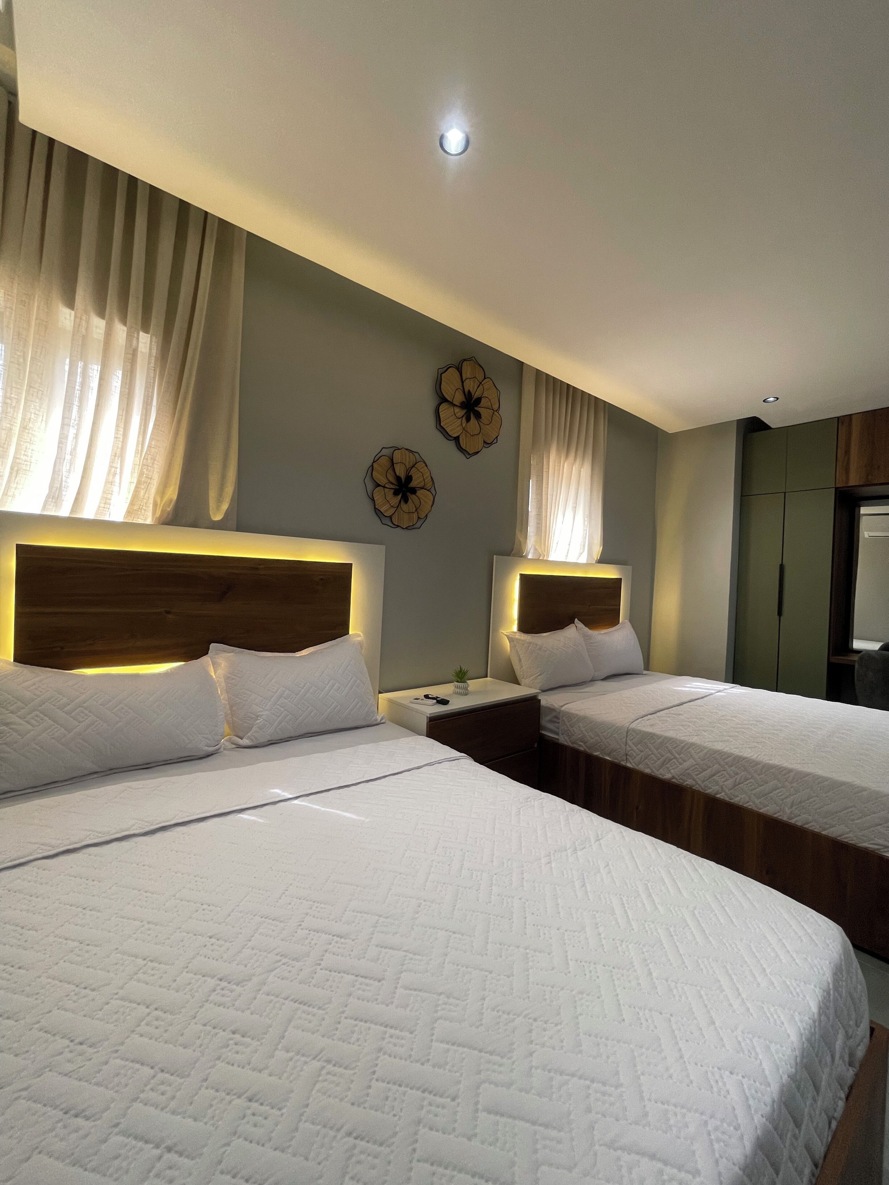 Una habitación de hotel con dos camas, una mesita de noche, una pequeña mesa y un reloj de pared.
