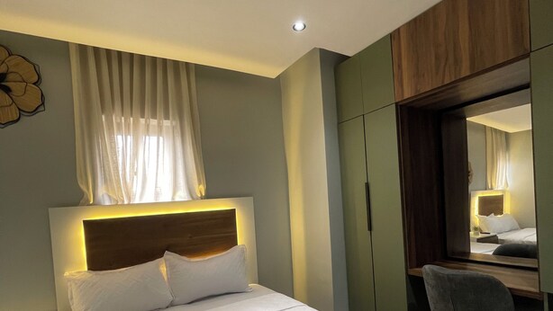 Quarto de hotel com uma cama grande, uma escrivaninha e um guarda-roupa.