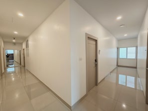 A corridor with a door on the right, a staircase at the end, and a window on the far wall. - Hada House near Yanhee Hospital (Bangkok)