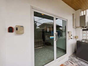 Una stanza con una porta finestra scorrevole, un piccolo riscaldatore e un interfono a parete.