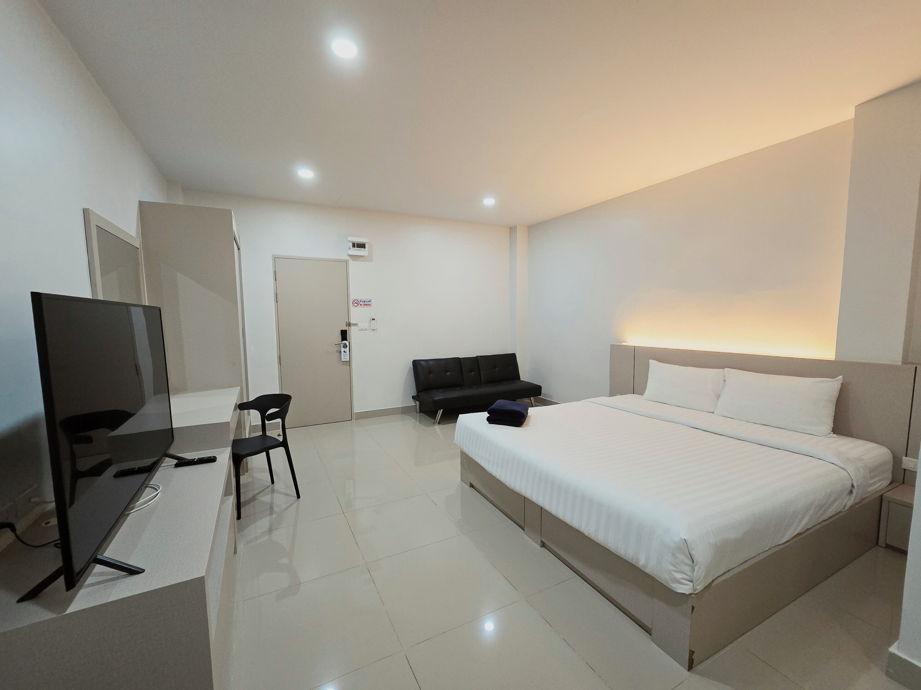 Una habitación de hotel con una cama, un escritorio con una silla, un televisor y una puerta.
