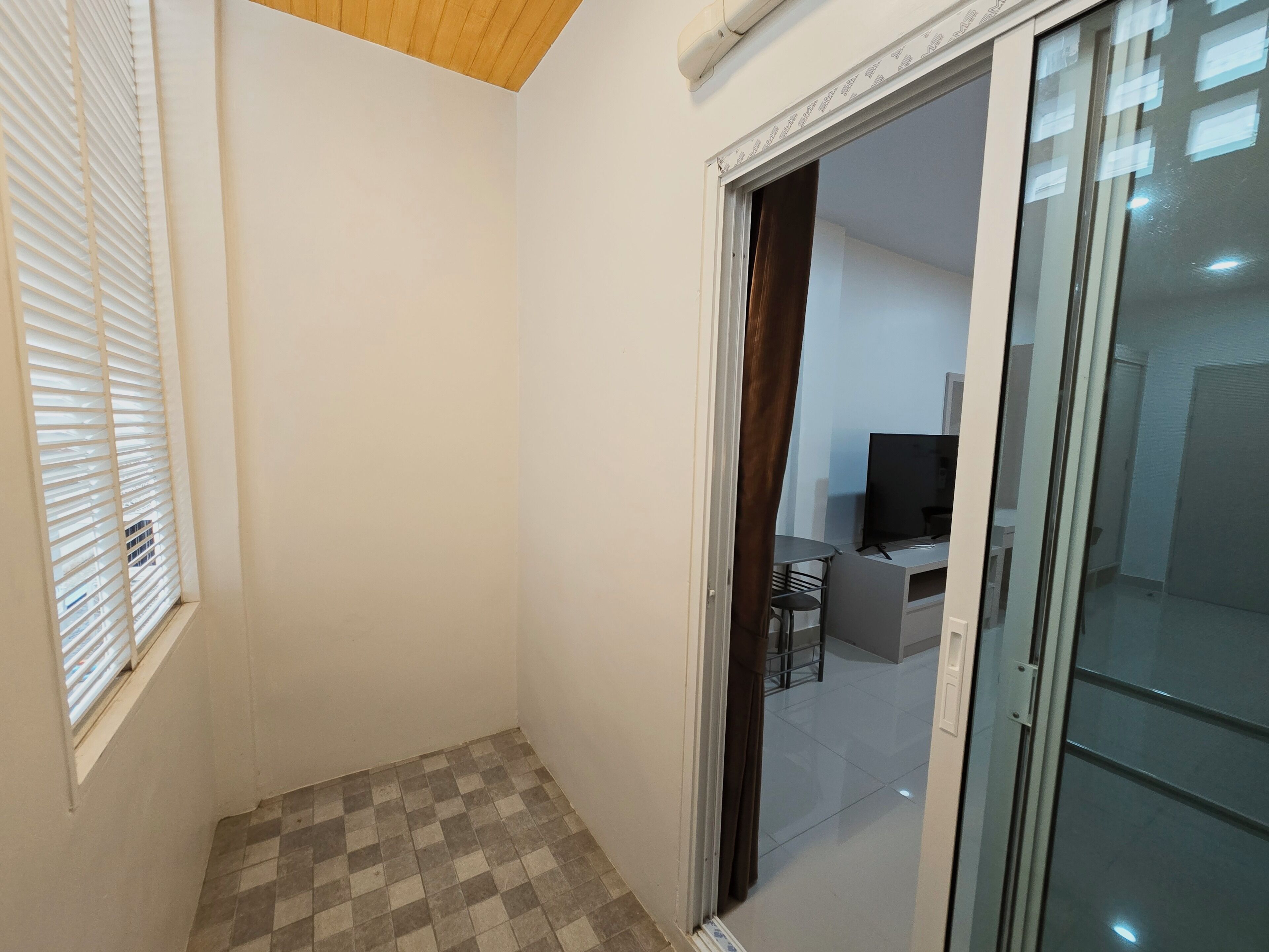 A room with a checkered floor, a desk with a chair, and a television.