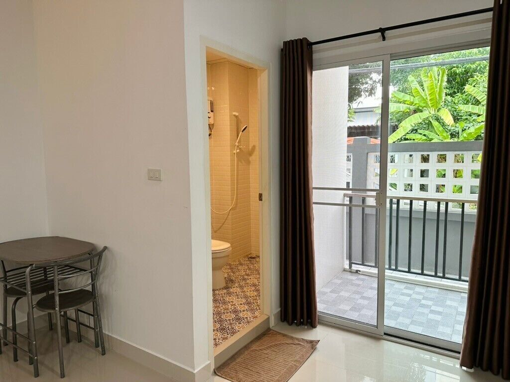 Een badkamer met een douche, toilet en een klein tafeltje met stoelen.