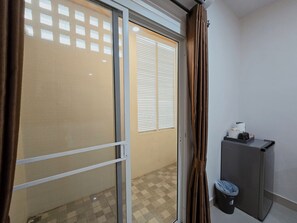 Una stanza con una porta scorrevole in vetro, un tavolino con una macchina da caffè e un cestino.