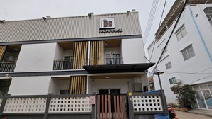 A multi-story building with a gated entrance, a balcony on the second floor, and a sign indicating it is a hotel.