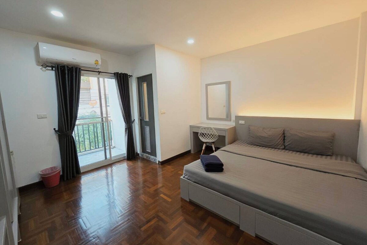 Una camera d'albergo con un letto, una scrivania, una sedia e un balcone con tende.