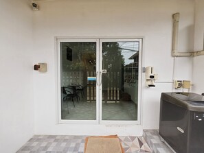 Una stanza con una porta a vetri scorrevoli che dà su uno spazio esterno con tavolo e sedie.
