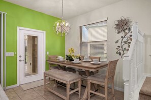 A dining area with a wooden table, chairs, and a chandelier. - 5BR Solterra Escape w/ Private Pool & Themes (Davenport)