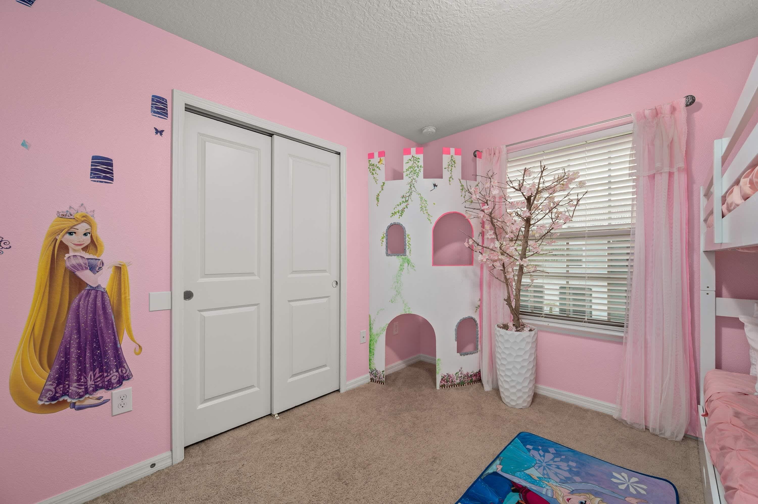 A pink-themed room with a princess mural, a white door, a window with blinds, and a bunk bed.