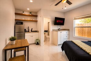 Une chambre d’hôtel compacte comprenant un coin cuisine, un lit, une télévision et une fenêtre donnant sur un paysage agréable.
