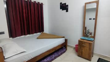 A bedroom with a single bed, a wooden nightstand, a mirror, and a red curtain.