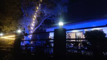A building with a blue-lit exterior, a visible entrance, and a tree with string lights.