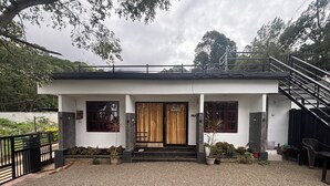 A modern two-story house with a covered porch, a staircase, and a gravel driveway.