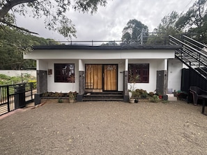 Una casa moderna de dos pisos amb un porxo cobert, una escala i un camí d'accés de grava.