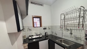 A compact kitchen with a gas stove, a sink, and a drying rack.
