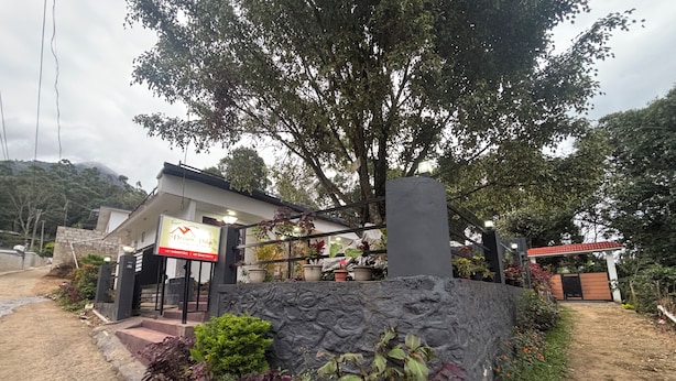 A building with a signboard, a stone wall, and potted plants.