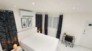 A bedroom with a bed, a desk, and a wall-mounted air conditioner. - The Little Heaven Retreats - Studio (Saint-martin)