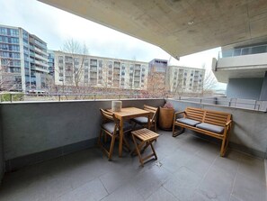 A balcony with a wooden table and chairs, a bench, and a potted plant. - Balcony, Dining and 2 Car Spaces (Barton)