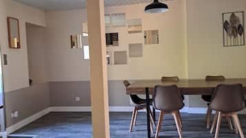 A spacious room with a large dining table, several chairs, and a ceiling fan.