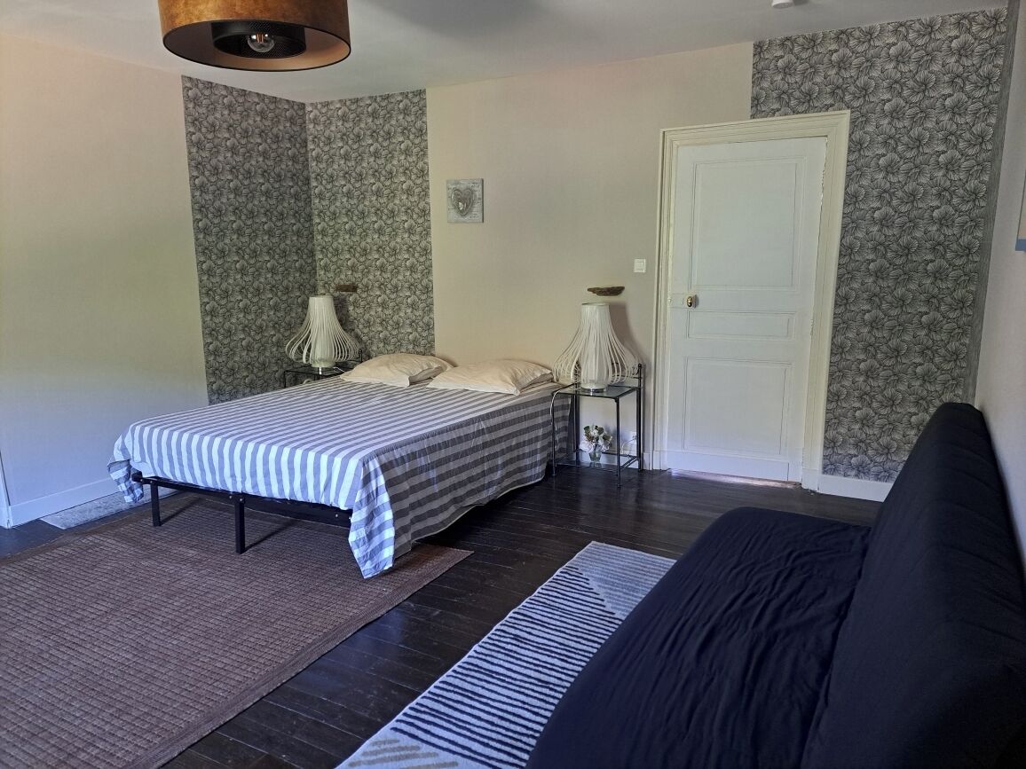 A bedroom with a bed, bedside tables, a lamp, and a door.