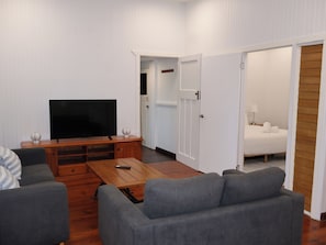 A living room with a flat-screen TV, a wooden coffee table, and grey sofas. - Gympie Cottage (Gympie)