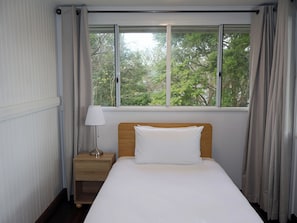 A hotel room with a bed, a nightstand, a lamp, and a window with curtains.