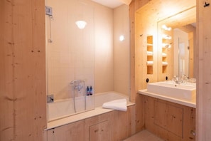 A modern bathroom with a wooden interior, a glass-enclosed shower, and a vanity with a mirror and lights. - Tannerhof - Mein Versteck In Den Bergen (Bayrischzell)