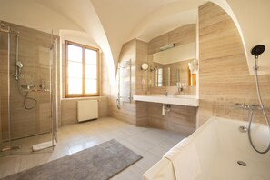 A modern bathroom with a glass shower, a bathtub, and a vanity with a mirror. - Hotel Belcredi (Brno)