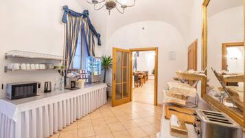Una cocina de hotel con barra de buffet, microondas, cafetera y tostadora.
