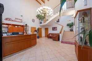 A hotel lobby with a reception desk, a staircase, and a chandelier. - Hotel Belcredi (Brno)