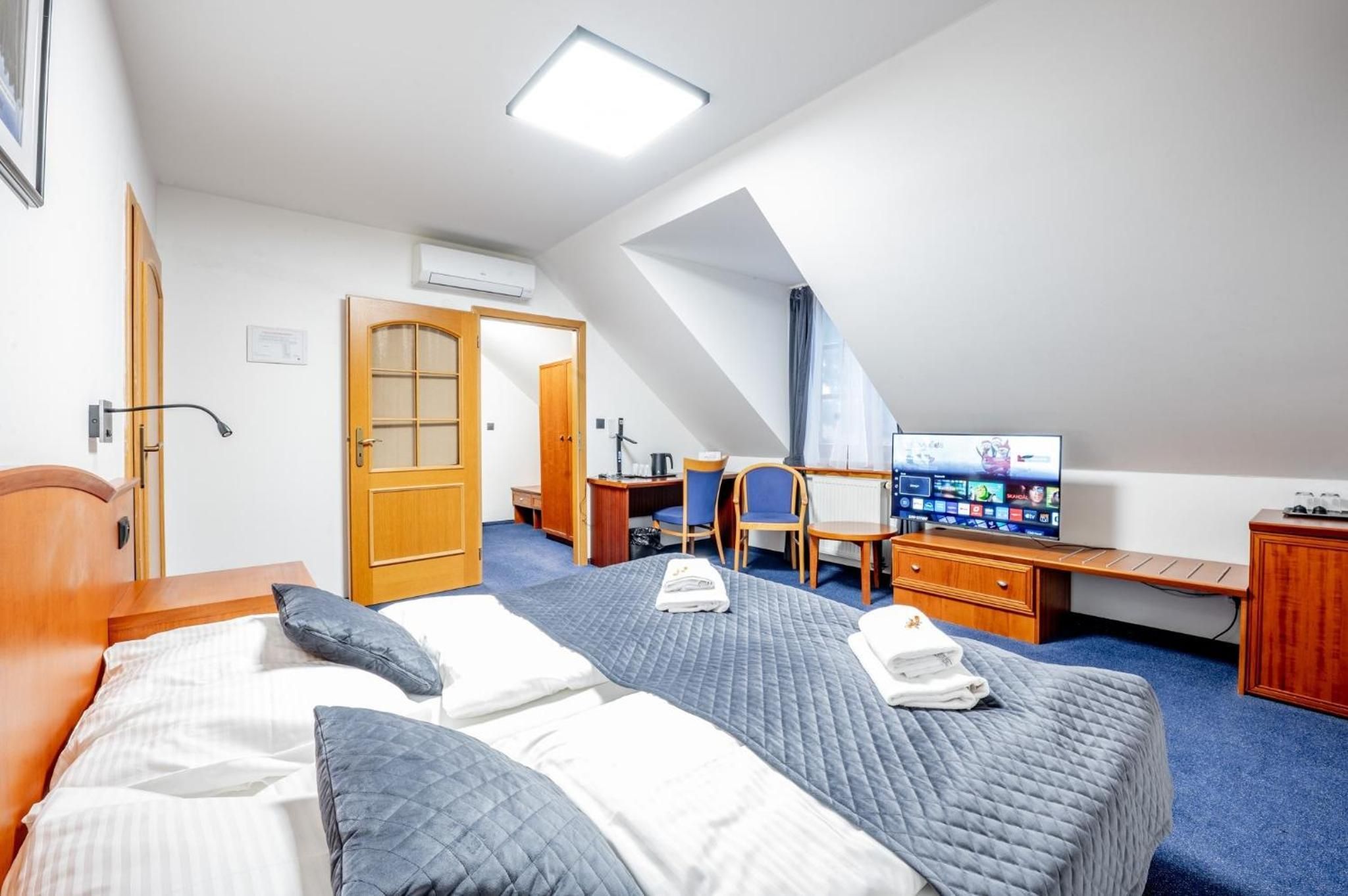 Una habitación de hotel con cama, escritorio, televisor y puerta.