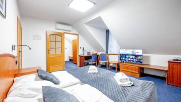 Una habitación de hotel con cama, escritorio, televisor y puerta.