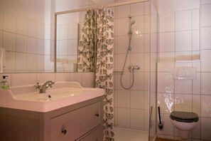 A bathroom with a sink, mirror, shower, toilet, and a patterned shower curtain. - Oldenburger Mvºhle (Oldenburg)