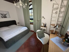 Un dormitorio con una cama, un escritorio con lámpara, una silla y un armario.